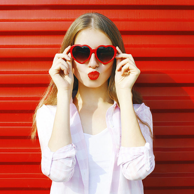 Jeune fille avec rouge à lèvres rouge sur fond rouge (Istock)