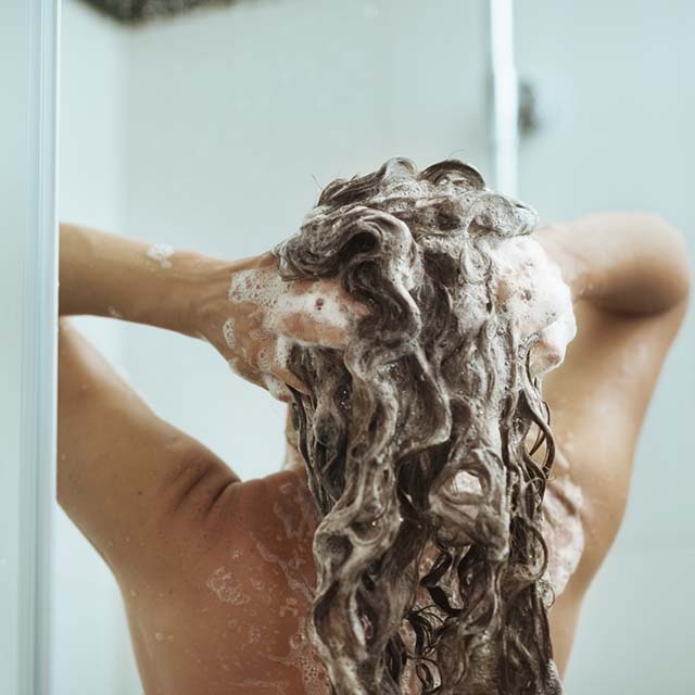Femme sous la douche en train de se laver les cheveux (iStock)
